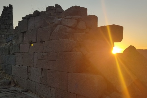 Photograph of archaeological site with sun setting behind it