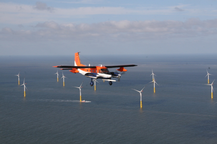 Forschungsflugzeug fliegt über Windpark