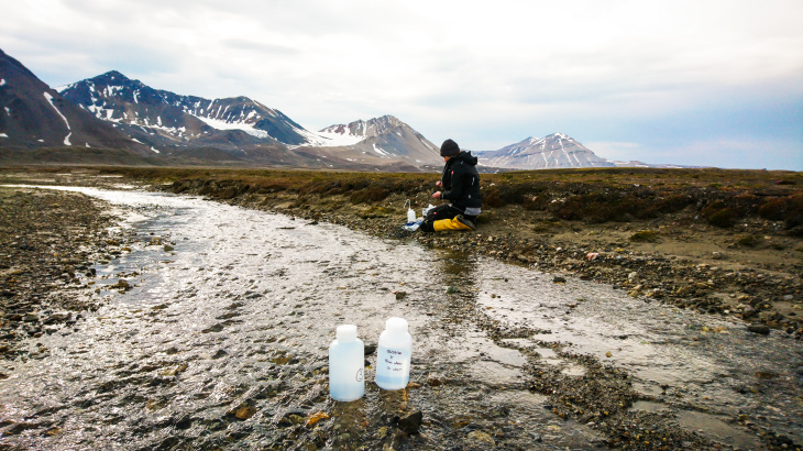 Claudia Schmidt nimmt Wasser- und Sedimentproben an einem Schmelzwasserfluss des Gletschers „Midtre Lovénbreen“.