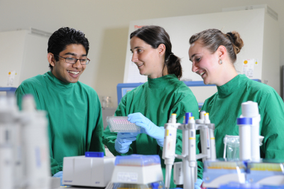 Schülerinnen und Schüler lachen während sie im Labor arbeiten